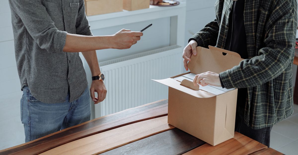 Cliente prenant une photo avec son smartphone d'un produit qu'elle vient de recevoir, exemple de contenu généré par les utilisateurs (UGC)